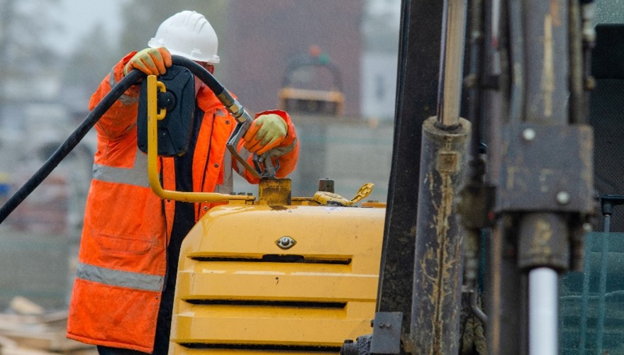 construction worker putting gas in an excavator